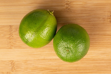 Group of two whole sour green lime flatlay on light wood
