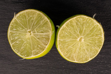 Group of two halves of sour green lime flatlay on grey stone