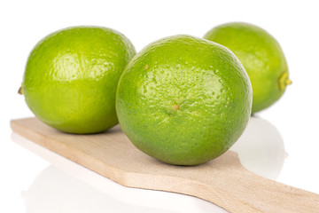 Group of three whole sour green lime on wooden cutting board isolated on white background