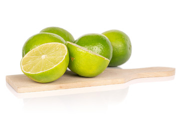 Group of four whole two halves of sour green lime on wooden cutting board isolated on white...