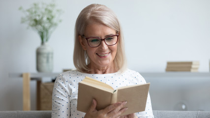 Elderly woman in glasses reading new book