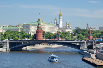 Summer view of the Moscow Kremlin, the Big Stone bridge and floating on the Moscow river pleasure boat. Moscow, Russia