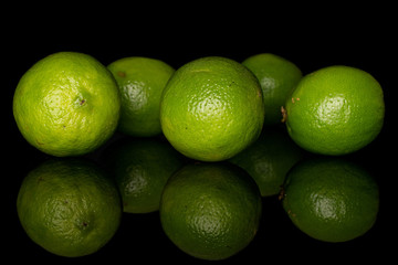 Group of five whole sour green lime isolated on black glass