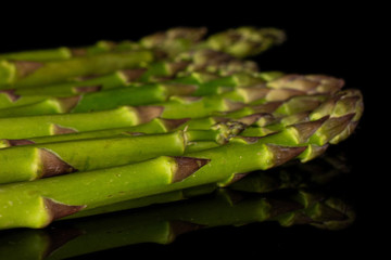 Lot of whole arranged healthy green asparagus isolated on black glass