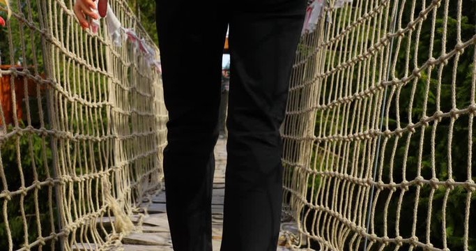 Older women with backpack passing Himalayan sidewalk path Skywalk wooden construction with colored flags during windy, sunny autumn day captured in Radhost Pustevny area slow motion 4k 60fps