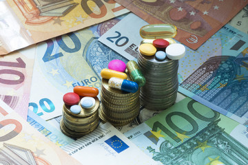 Medicine treatment cost concept with pills and drugs and pile of money or coins