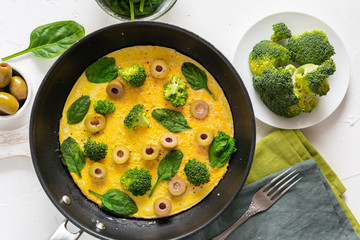 Omelette with broccoli, spinach and olives in a pan. Frittata - italian omelet with green vegetables.