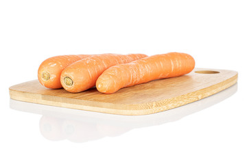 Group of three whole fresh orange carrot on bamboo cutting board isolated on white background