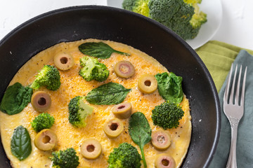 Omelette with broccoli, spinach and olives in a pan. Frittata - italian omelet with green vegetables.