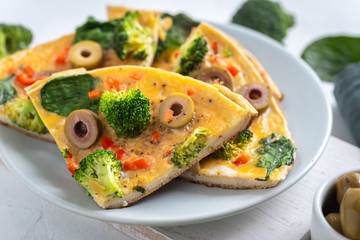 Omelette with broccoli, spinach and olives on a plate. Frittata - italian omelet with green...