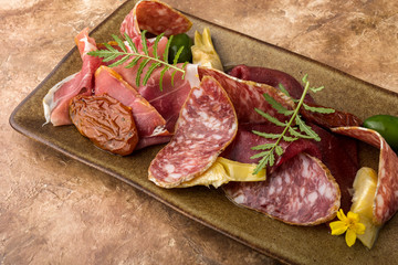 Italian set, bresaola, Parma ham, salami, sun-dried tomatoes, olives, thin slices, dish, brown background