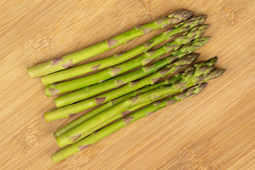 Lot of whole healthy green asparagus flatlay on light wood