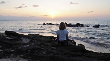 Fototapeta na wymiar girl meditating practising yoga at the beach kimono thailand sunset