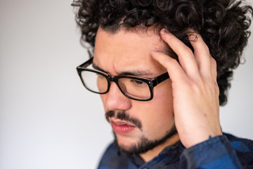 Obraz premium Latin American man with curly hair having a headache, upset expression, on a white background 