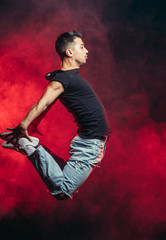 Fototapeta na wymiar portrait of vigorous dancer male dancing street dance, jump in the air isolated over smoky background