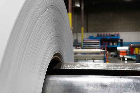Roll of Steel on factory decoiler machine. used to make roofing sheets. Metal roll being uncoiled
