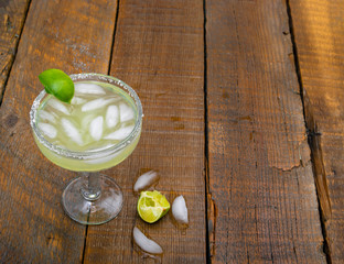 Margarita alcoholic cocktail drink with a lime on a rustic wooden background