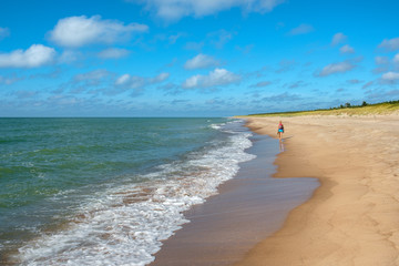 Woman walking on sandy colourfull beach in sunset,