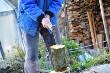 Splitting wood with an ax into smaller logs in traditional way 