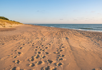 Fototapeta na wymiar wild beach coastline with footprints. evening lights