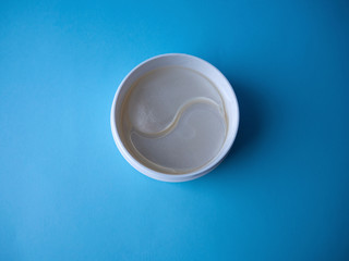 Pearl hydrogel eye patch in a white jar close up top view. Pack of under-eye masks for reducing dark circles, puffiness and fine lines. Beauty skin care for women and men.