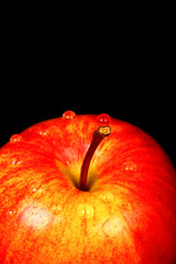 Red eating apple isolated on a black background with water drops
