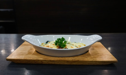Baked spinach and cheese in a white cup ready The wooden table on the background