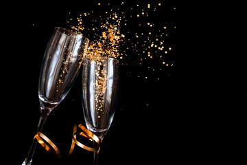 Two champagne glasses with golden sparkles over black background. Happy new year. © Anastassiya 