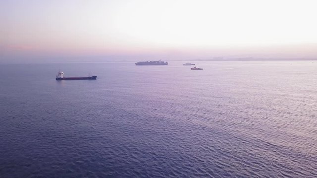 Flight over ocean water and approaching several cargo ships.