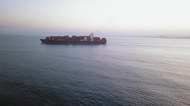 Large container ship at sea, loaded with various container brands. ULCV container ship sails on open water fully loaded with containers and cargo.