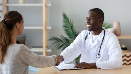 Pleasant african american male doctor shaking hands with patient.