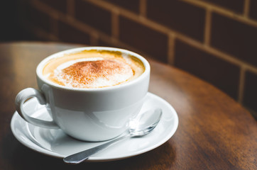 close up modern hot black coffee the cappuccino on wood background with coffee bubble foam pattern and texture in white cup looking and feel so delicious on glasses table in coffee shop.