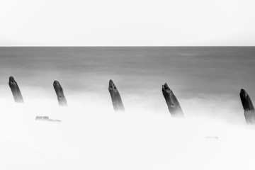 Image longue exposition noir et blanc de brise-lames en bois sur la côte est de l& 39 Angleterre, Royaume-Uni