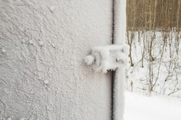 metal door and door handle and keyhole are covered with frost. severe frosts. door freezes. icy handle and lock covered with snowflakes.