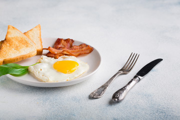 English breakfast concept. Fried eggs, sliced bacon and slices of toast on a white background
