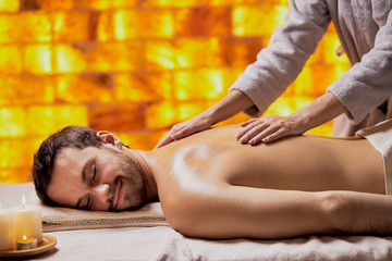 Handsome caucasian man getting massage in the beauty salon, spa salon, naked skin. Young bearded man relaxing,yellow wall background in spa - Powered by Adobe