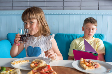 Children eat in a cafe eat Italian pizza and drink cola.