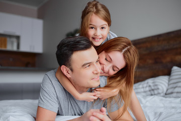 young caucasian parents spend time together at home lying on bed, smile, isolated in room