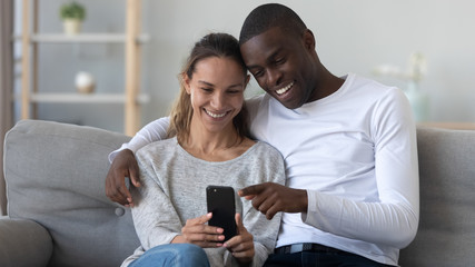 Happy young mixed race family couple using mobile phone.