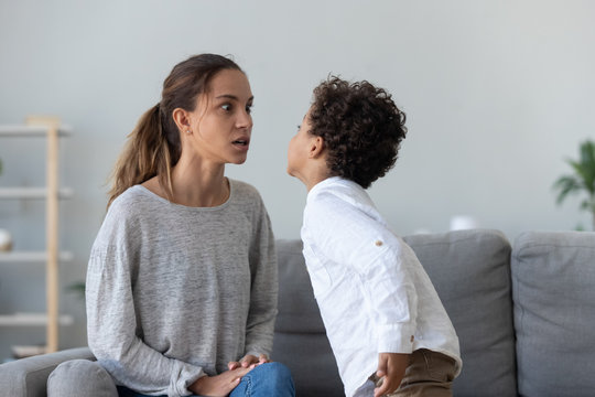 Provocative mixed race little kid demonstrating impolite behavior to mom.