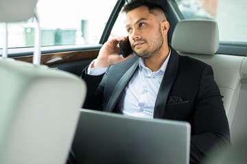 young handsome man confidently looking, talking on phone with business partner, busy man sit in executive car