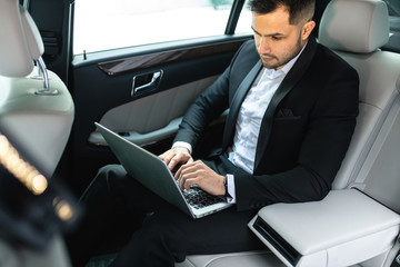 Young caucasian man with beard and dressed in formal wear sit with laptop and work, business people...