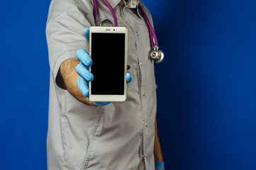 Copy space portrait of a doctor in gloves and a stethoscope on his neck holding a smartphone with a screen to the viewer. Mobile diagnostics. Modern technologies in medicine
