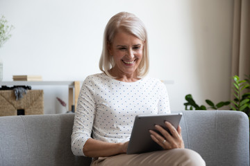 Elderly woman holding tablet funny spending free time watching comedy