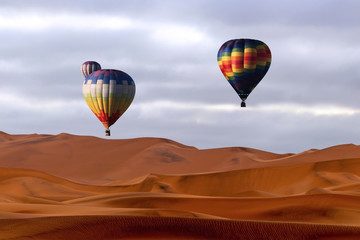 Fototapeta na wymiar Beautiful Colorful Hot Air Balloons and dramatic clouds over the sand dunes in the Namib desert