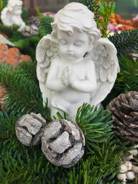Small white angel statue praying in a fir tree arrangement