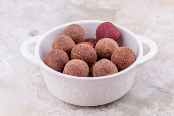 Homemade Raw Vegetarian Cacao Energy Balls in White Bowl on Marble Background. Organic Healthy Truffles from Nuts and Dates. Concept of Natural Vegan Handmade Dessert