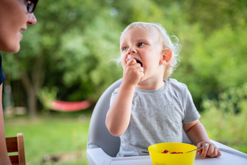 Baby eating with his mom outdoor