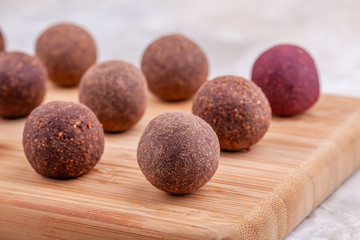 Close Up of Homemade Raw Vegan Cocoa Energy Balls on Wooden Tray on Table. Healthy Chocolate Colorful Candy from Nuts and Dates. Concept of Natural Vegetarian Handmade Dessert