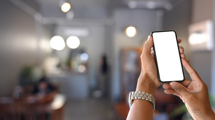Man's hands holding mockup smartphone with empty screen.